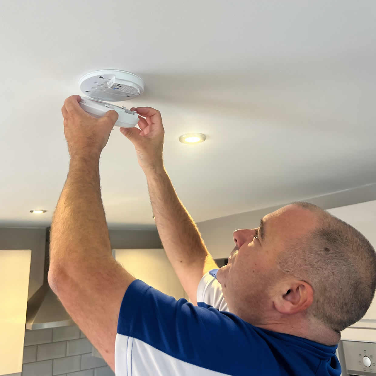Smoke alarm installer fitting an alarm in a Saint Helens property